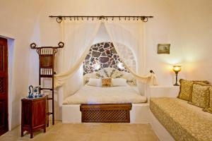 1 dormitorio con cama con dosel y sofá en Alexander's Suites en Oia