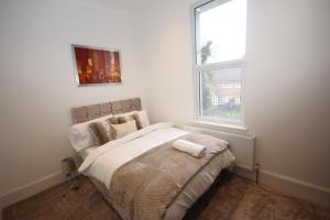 1 dormitorio con 1 cama y ventana grande en Great West Road Apartments [ Flat C ], en Londres