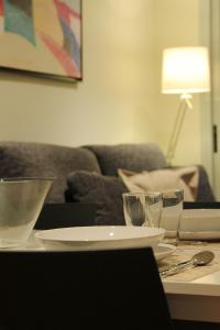 a table with plates and glasses on it with a couch at Alguera Apartments Industria in Barcelona