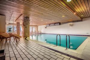 a swimming pool with a table and chairs in a building at Sporting Clubresidence in San Martino di Castrozza