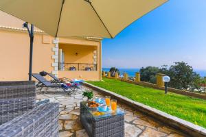 a patio with a table with food and an umbrella at Villa Seasunrise in Perama