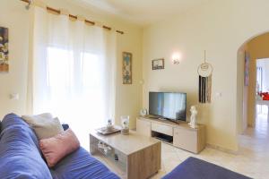 a living room with a blue couch and a tv at Villa Seasunrise in Perama