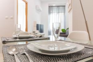 a dining room table with a plate and glasses on it at ALC - Apartamento céntrico en calle Mayor in Alicante