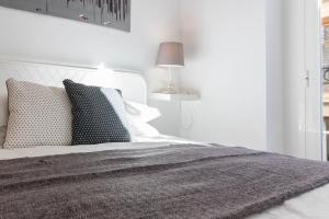 biała sypialnia z łóżkiem z poduszkami i lampą w obiekcie ALC - Apartamento céntrico en calle Mayor w Alicante