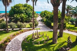 een tuin met palmbomen en een loopbrug bij The Orangers Beach Resort and Bungalows All Inclusive in Hammamet