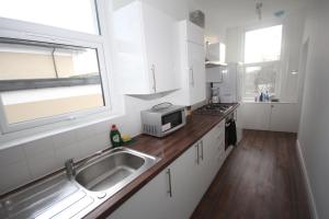 cocina blanca con fregadero y microondas en Great West Road Apartments [ Flat C ], en Londres
