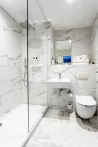 a white bathroom with a shower and a toilet and a sink at Palm Court Hotel in Aberdeen