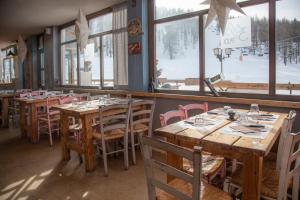 un restaurante con mesas y sillas de madera y ventanas en Hotel Monte Triplex, en Sauze dʼOulx