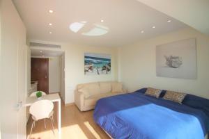 ein Schlafzimmer mit einem blauen Bett und einem Sofa in der Unterkunft Estudio de Lujo CasaTuris en el Corazón de Alicante A114 in Alicante