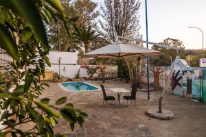 a patio with a table and chairs and an umbrella at Back2Roots Backpackers in Windhoek