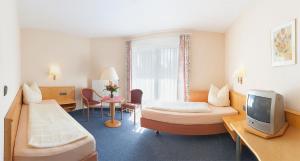 a hotel room with two beds and a tv at Annas Gästehaus in Hallerndorf