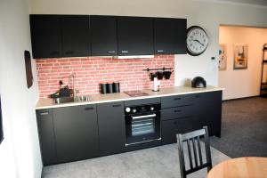 a kitchen with black cabinets and a brick wall at APARTAMENTY VINCI in Krasnystaw