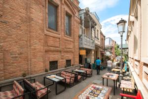 a street with tables and chairs and a brick building at Hotel Opinion in Tbilisi City