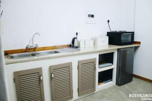 eine Küchentheke mit einer Spüle und einer Mikrowelle in der Unterkunft Bosveldrus Gastehuis in Vaalwater