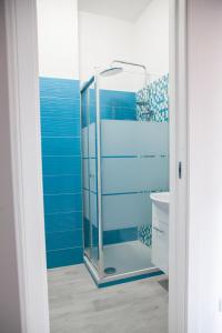 a bathroom with a glass shower with blue walls at Poly's House in Torre Annunziata