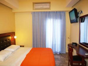 Dormitorio con cama, escritorio y TV en Hotel Filoxenia, en La Canea
