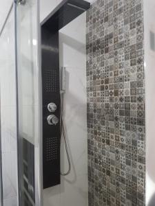 a shower with a glass door and a tile wall at Sweet home in Kenitra