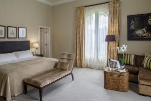 a room with a bed, chair and a lamp at Bowood Hotel, Spa, and Golf Resort in Chippenham