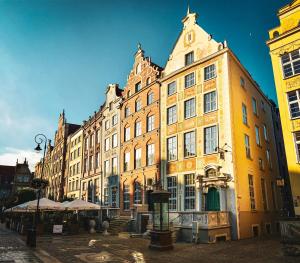 a large yellow building with a clock on the top of it at IBB Hotel Gdańsk in Gdańsk