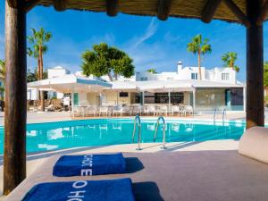 - une piscine avec des chaises longues et des parasols dans un complexe dans l'établissement Boutique Hotel H10 White Suites - Adults Only, à Playa Blanca