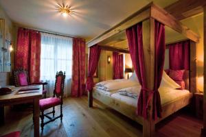 a bedroom with a canopy bed with a desk and a desk at Romantik Hotel Fürstenhof in Landshut