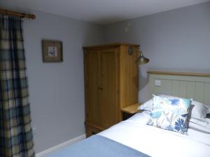 a bedroom with a bed and a wooden cabinet at Bed and Breakfast accommodation near Brinkley ideal for Newmarket and Cambridge in Newmarket