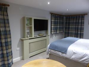 1 dormitorio con 1 cama, TV y cortinas en Bed and Breakfast accommodation near Brinkley ideal for Newmarket and Cambridge, en Newmarket