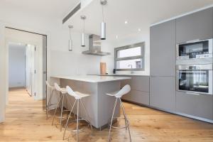 eine Küche mit weißen Wänden und einer Insel mit Barhockern in der Unterkunft HHBCN Beach Apartment Gava #2 in Gavà