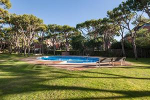 ein Schwimmbad mit zwei Bänken in einem Park in der Unterkunft HHBCN Beach Apartment Gava #2 in Gavà