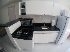 une cuisine avec des placards blancs et un comptoir noir dans l'établissement STUDIO 102 - Manaíra, à João Pessoa
