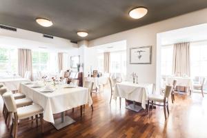 a dining room with white tables and chairs and windows at Hotel Radun in Luhačovice