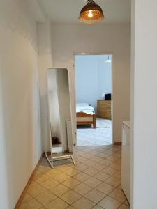a hallway with a mirror and a bed in a room at WHITE Apartment in Jabłonna