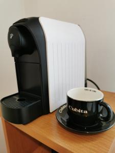 a coffee cup on a saucer next to a coffee maker at WHITE Apartment in Jabłonna