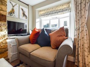 sala de estar con sofá y almohadas en Appletree Cottage en Bourton on the Water