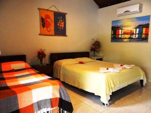 a bedroom with two beds and a painting on the wall at Pousada Cavalo Marinho in Pipa