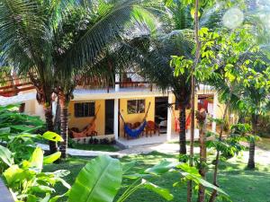 a house with palm trees in front of it at Pousada Cavalo Marinho in Pipa