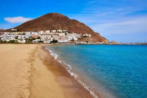 a beach with white houses on a hill next to the water at Apartamento del Mar San Jose in San José