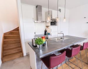 a kitchen with a counter and pink chairs at Gästeapartment auf einem Bauernhof in Bad Bentheim