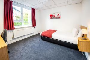 1 dormitorio con 1 cama y una ventana con cortinas rojas en Lancaster University, en Lancaster