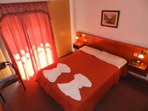 Un dormitorio con una cama roja con toallas. en Sun-Shine Hotel en San Clemente del Tuyú