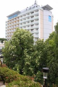 セゲドにあるAquarius Apartmanの木が目の前に建つホテルの建物