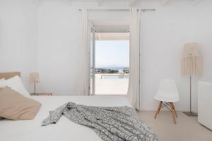 a white bedroom with a bed and a window at White Santa Maria Villa in Santa Maria