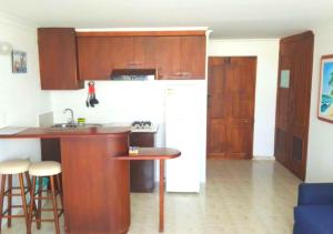 a kitchen with wooden cabinets and a white refrigerator at Apartamento para parejas frente a la playa San Andres in San Andrés
