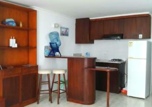 a kitchen with a counter with stools and a refrigerator at Apartamento para parejas frente a la playa San Andres in San Andrés