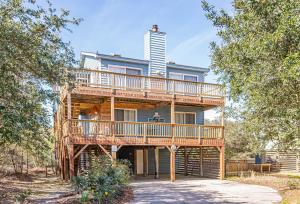 a tree house with a deck and a tall building at Misty Blue in Corolla