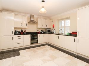 uma cozinha com armários brancos e piso em azulejo em 11 Eagle Parade em Buxton
