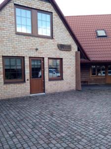 a brick building with a door and a brick driveway at Cozy House Mētriņi in Ķekava