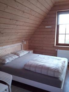 a bed in a wooden room with a window at Cozy House Mētriņi in Ķekava