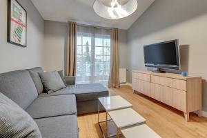 a living room with a gray couch and a flat screen tv at Apartament Patio Mare by Grand Apartments in Sopot