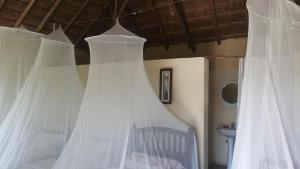 a bedroom with white curtains on a bed at Heritage Safari Lodge in Pakwach East